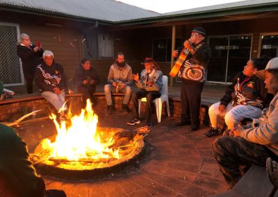 KBH survivors share stories and songs with family and friends around a fire at the Kinchela Boys Home site.